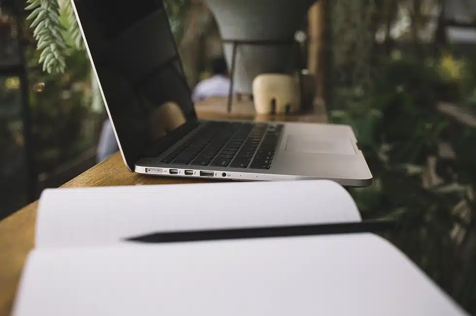 Ordinateur portable et carnet de notes sur une table en bois — illustration d’un article de blog sur la création et la gestion de contenu pour un site internet.